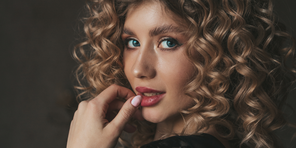 Donna che si asciuga i capelli con phon e spazzola rotonda per creare volume alla piega
